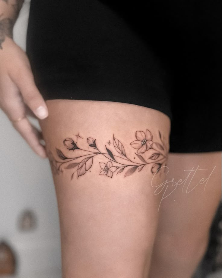 a woman's thigh with flowers on it and the word love written in cursive writing