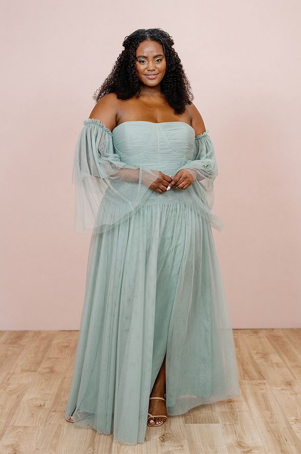 a woman in a dress standing on a wooden floor with her arms around her waist