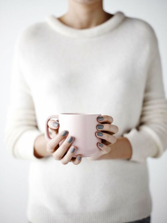 a woman holding a pink coffee cup in her hands