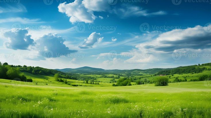 a green field with mountains and clouds in the background, under a blue cloudy sky