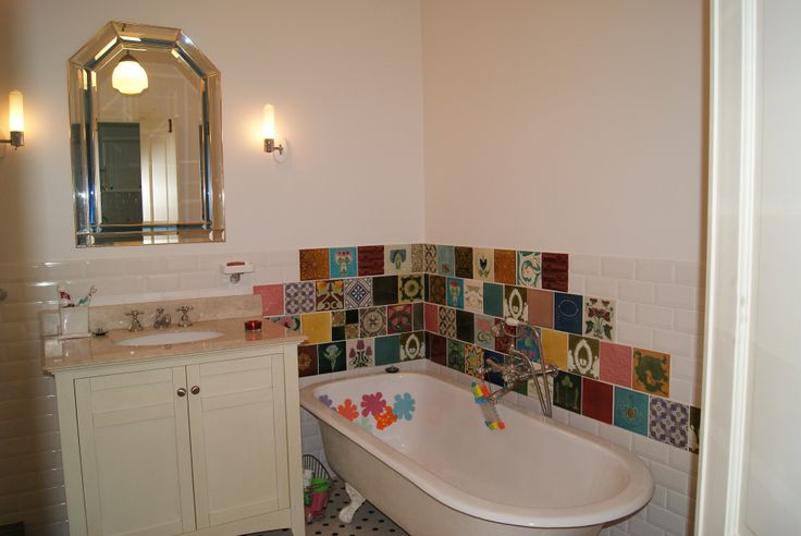 a bath tub sitting under a bathroom mirror next to a sink