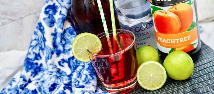 two glasses filled with liquid and limes next to bottles