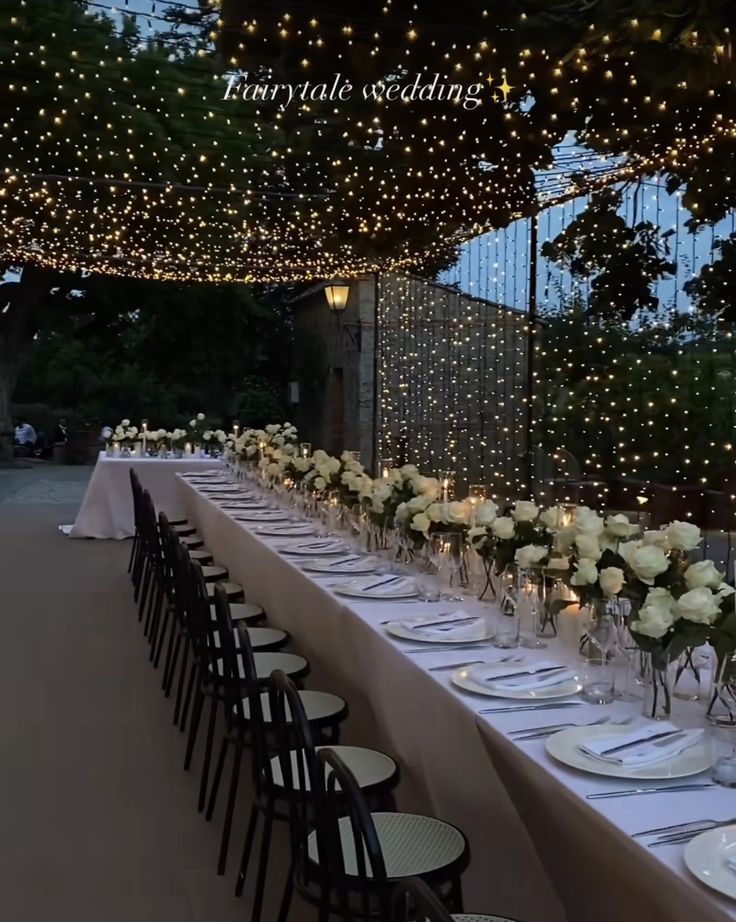 a long table is set up with white flowers and candles for an elegant dinner party