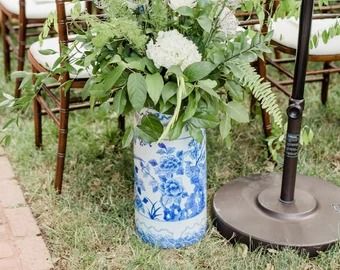 a blue and white vase filled with flowers next to an umbrella