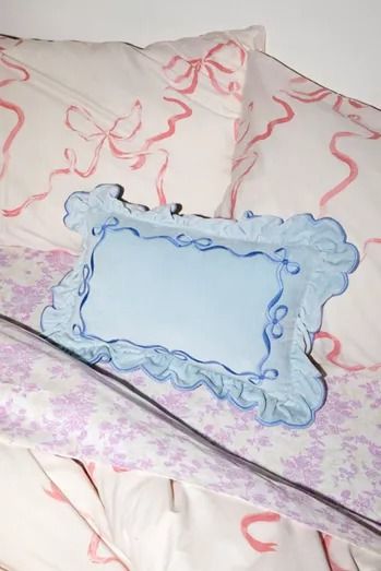 a bed with pink and blue sheets, pillows and a mirror on top of it