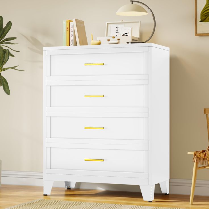 a white chest of drawers in a living room next to a chair and potted plant