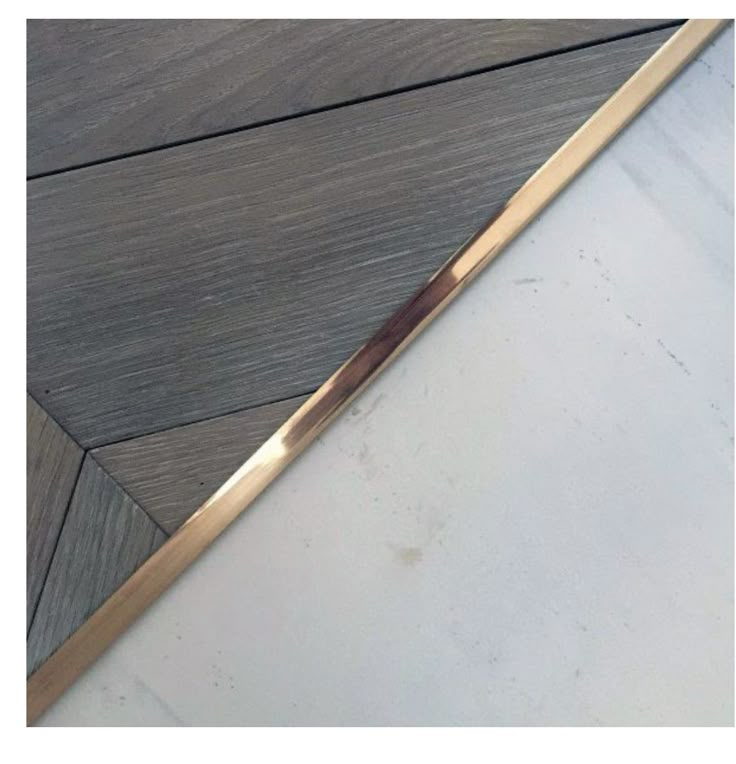 a close up of a wooden floor with a metal strip on it's side