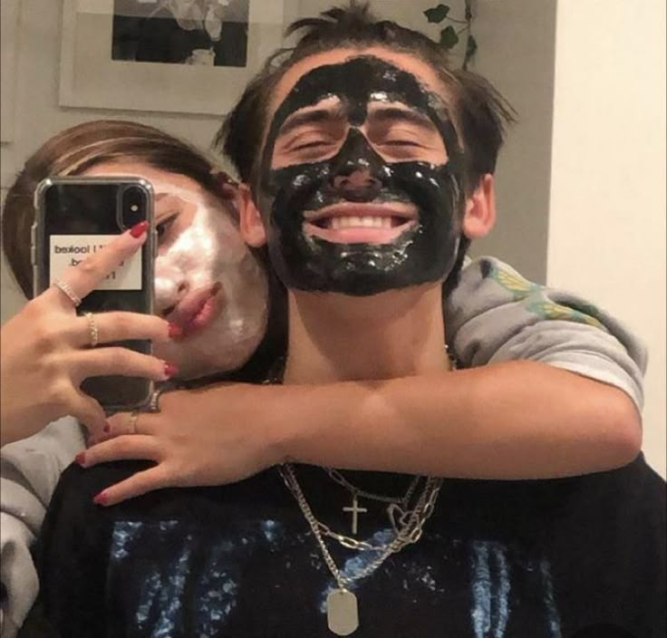 a man and woman with facial masks on taking a selfie