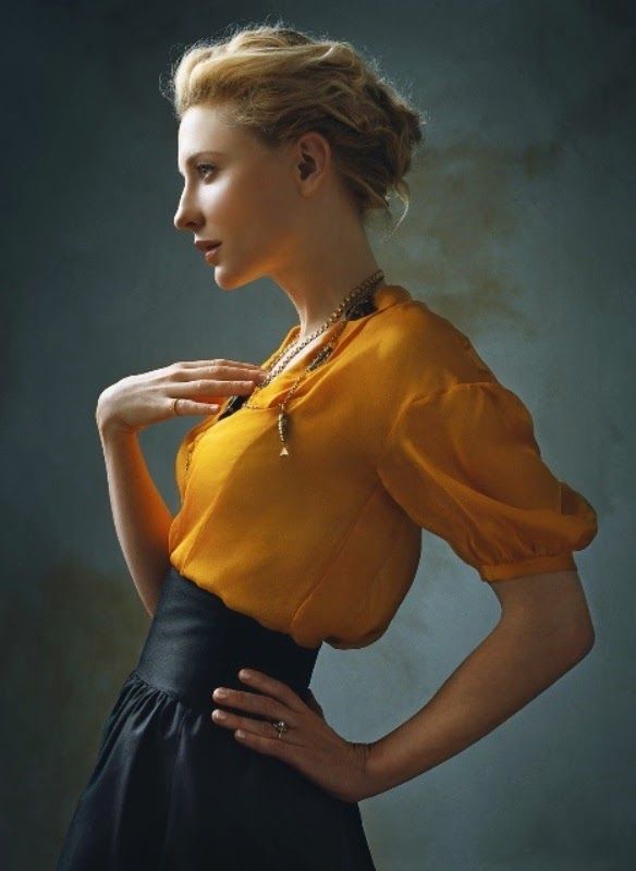 a woman in an orange top and black skirt posing for a photo with her hands on her hips