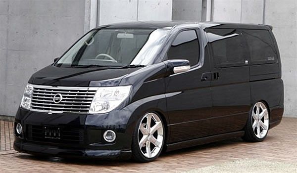 a black van is parked in front of a building with white trim and chrome rims