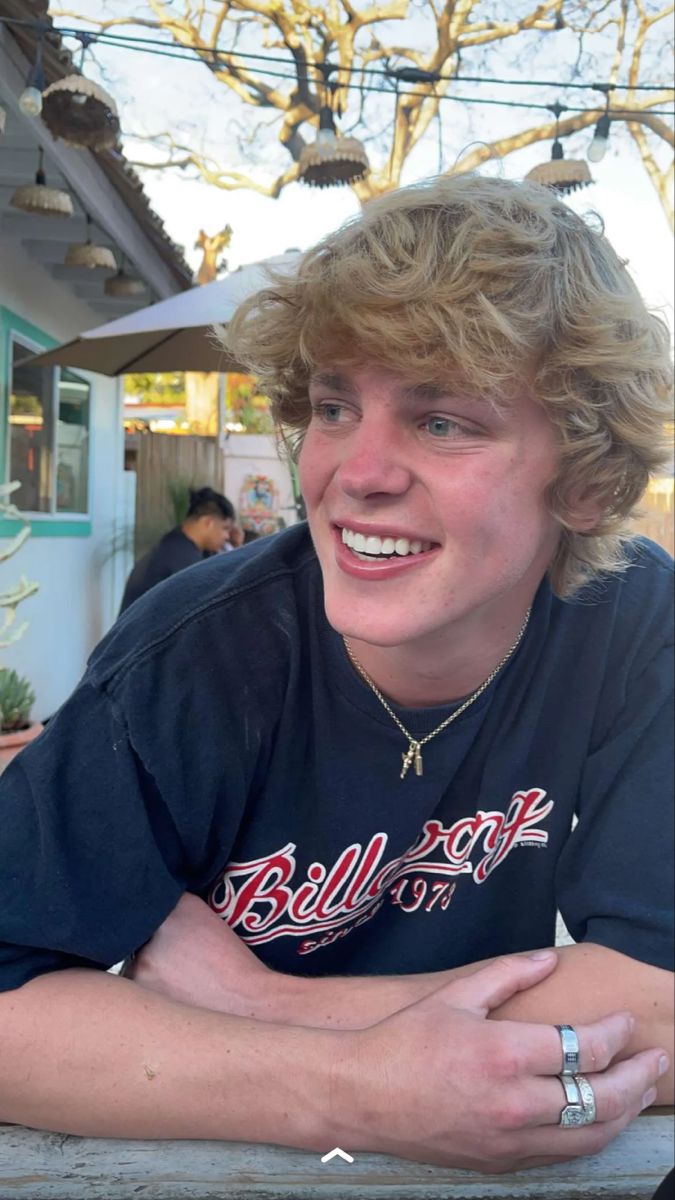 a young man sitting at a table with his arms crossed