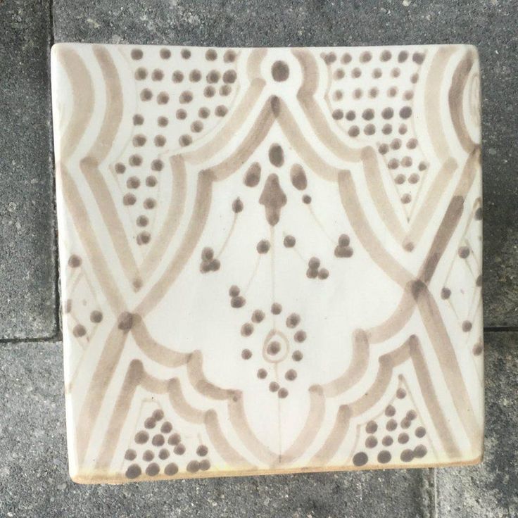 a close up of a tile on the ground with small holes in it's center