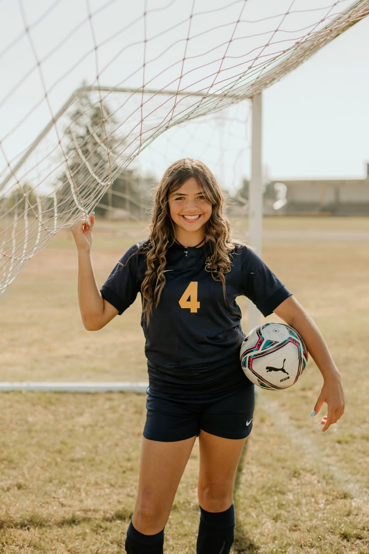 a female soccer player is posing with her ball