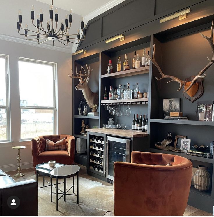 a living room filled with furniture next to a window covered in deer head mounted on the wall