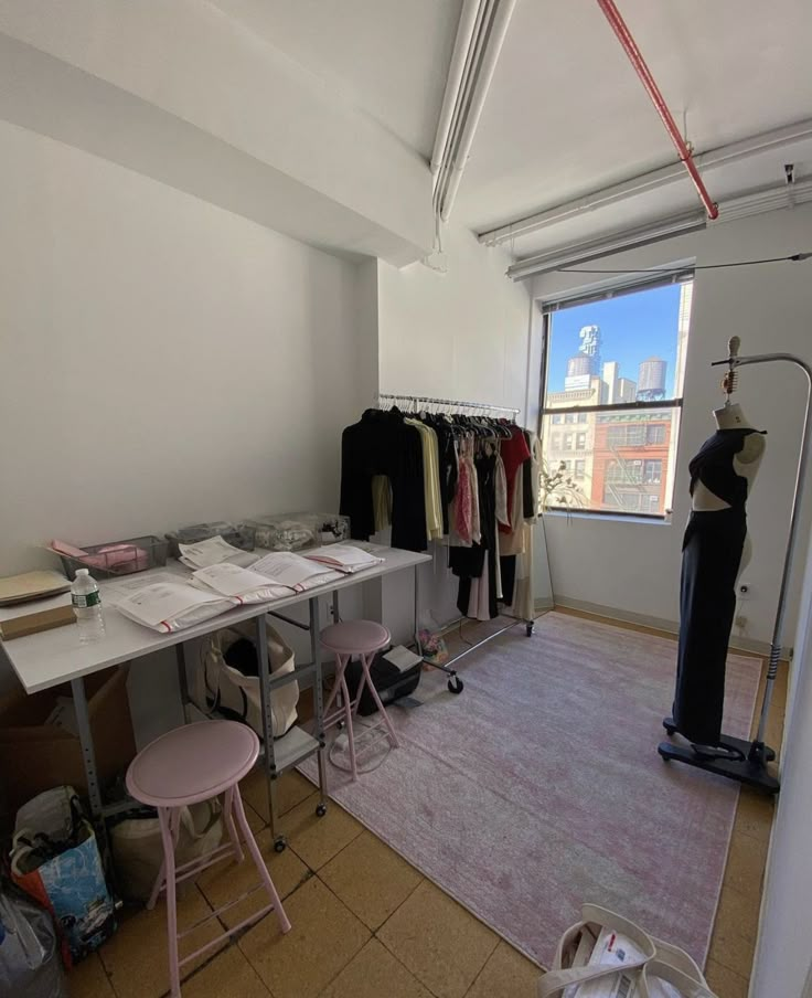 an empty room with clothes on hangers and other items in the corner near a window