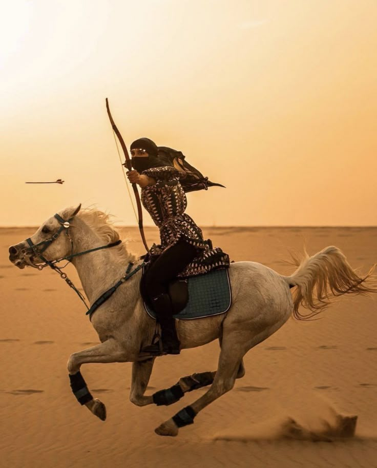 a woman riding on the back of a white horse in the middle of desert area