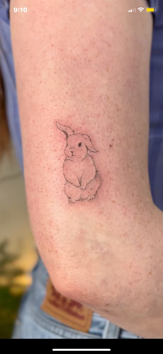 a small rabbit tattoo on the back of a woman's arm