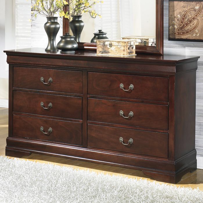 a dresser with two vases on top of it next to a mirror and rug