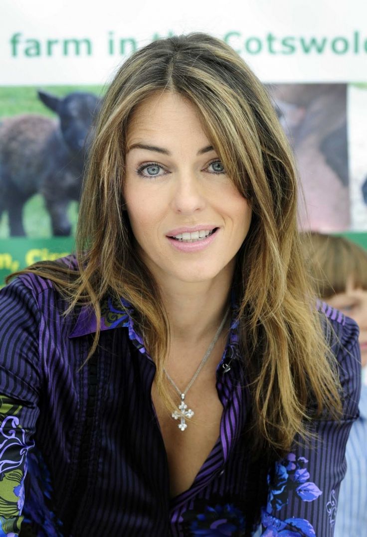 a woman with long hair sitting in front of a sign