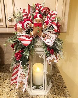 a lighted lantern decorated with candy canes, holly and a teddy bear