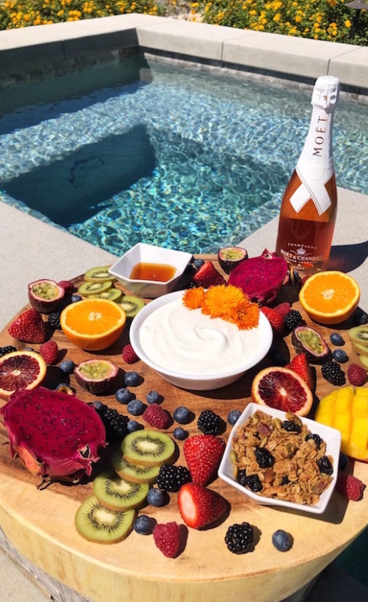 A large wooden board filled with sliced fruit, homemade vanilla yogurt, granola, and champagne sits next to a pool. Coachella Food, Poolside Brunch, Grad Brunch, Coachella Photos, Wishlist Board, Rosé Champagne, Brunch Board, Yogurt Granola, Best Brunch Recipes