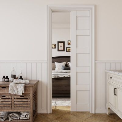 an open door leading to a bedroom with white walls and wood flooring on the other side