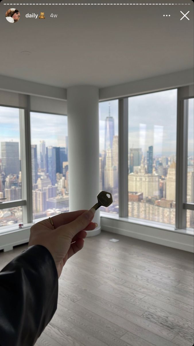 a person holding a key in front of a large window with cityscape on it