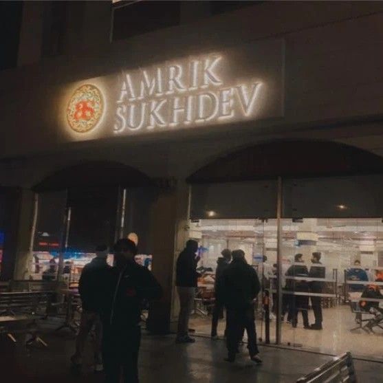 people are standing outside the entrance to an outdoor shopping area at night time, with lights on