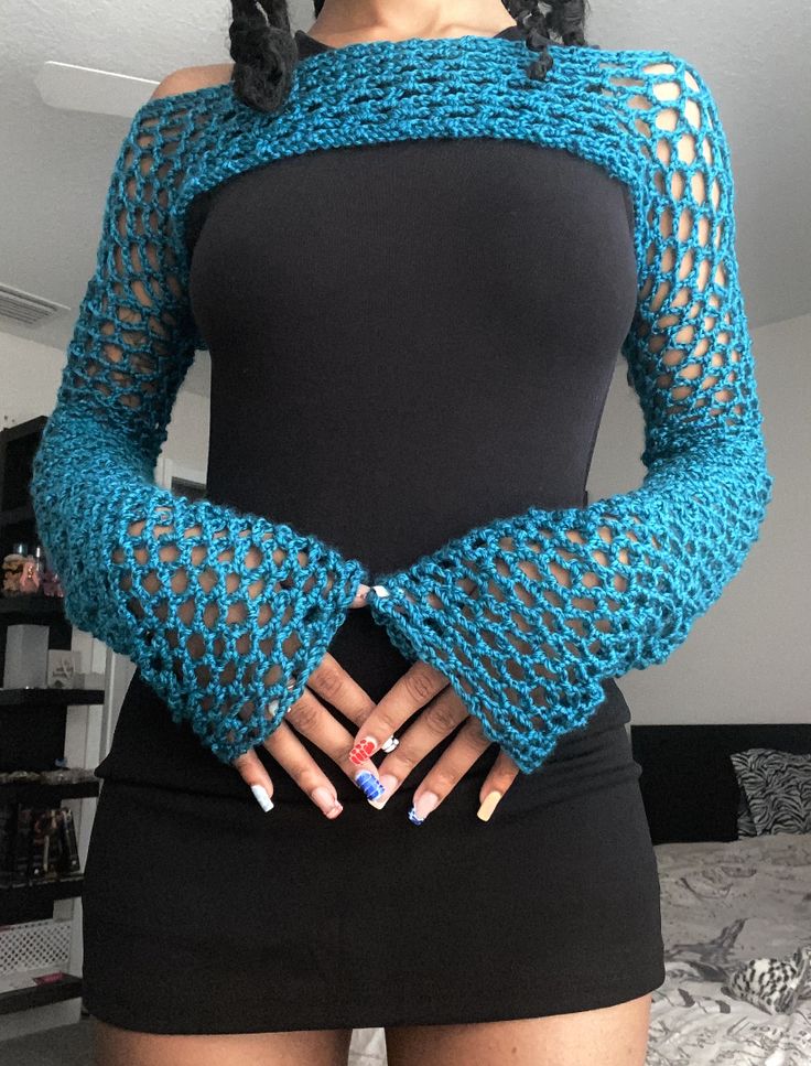 a woman with her hands on her hips wearing a blue knitted sweater and black dress