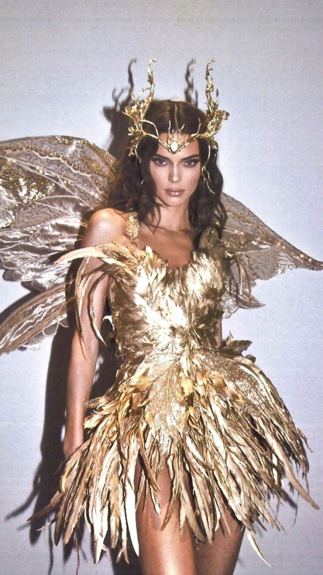 a woman in a gold costume with feathers on her head and wings around her body