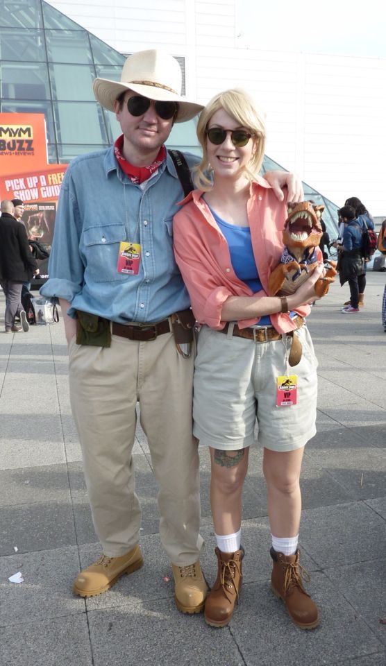 a man and woman standing next to each other in front of a building holding stuffed animals