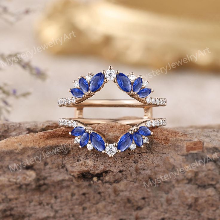 two blue and white diamond rings sitting on top of a rock