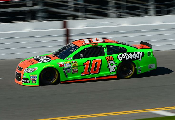 a green car driving down a race track with the number 10 godaddy on it