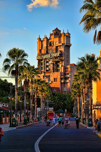 the hollywood tower hotel is surrounded by palm trees and people walking down the street in front of it