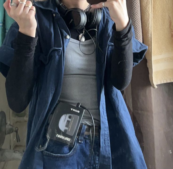 a woman taking a selfie in front of a mirror wearing headphones and holding a cell phone