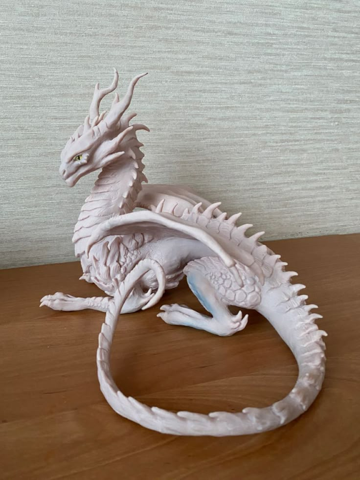 a white dragon figurine sitting on top of a wooden table next to a wall