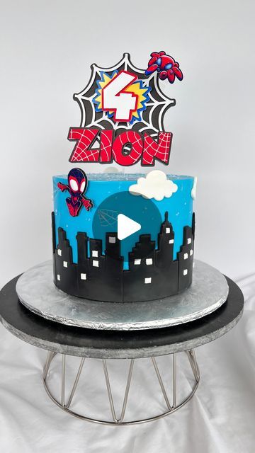 a spiderman themed birthday cake on top of a metal stand with a white background