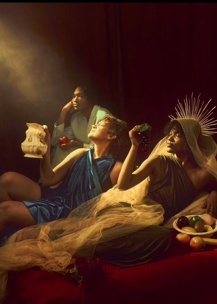 three women sitting on a bed with food in their hands and one holding a bottle