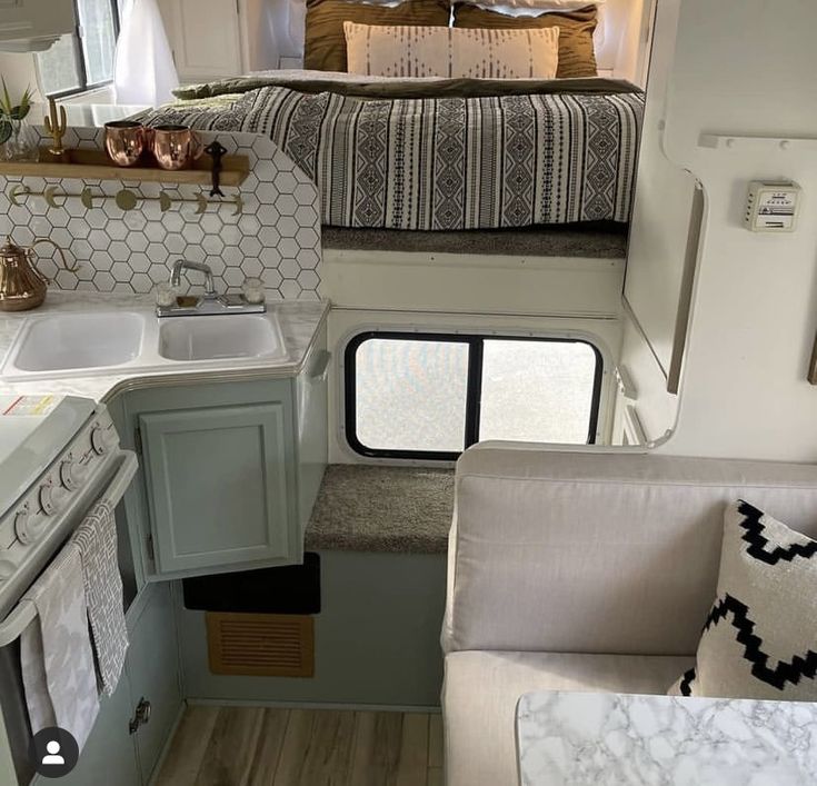 the interior of a camper with a bed, sink, and kitchen in it