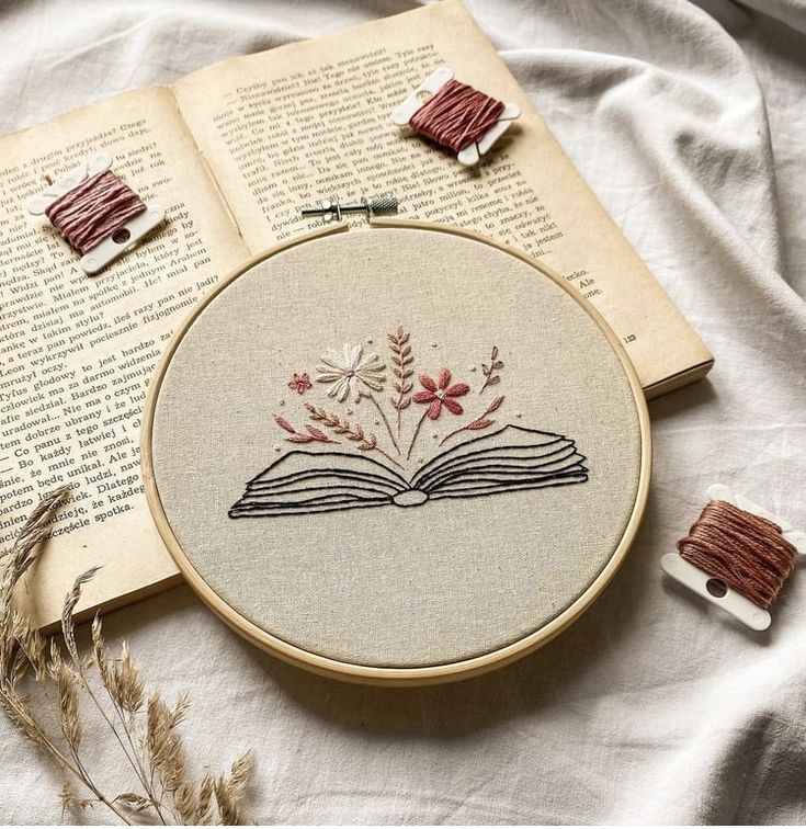 an open book with flowers on it next to some thread