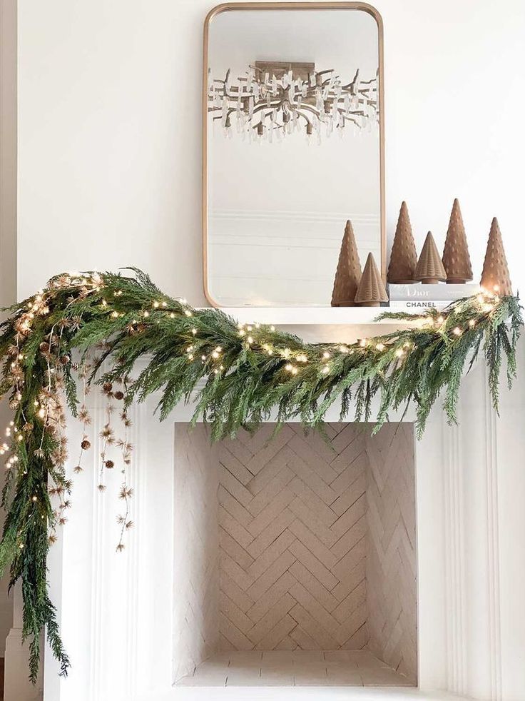 a mantel decorated with christmas garland and cones on it's mantle, next to a mirror