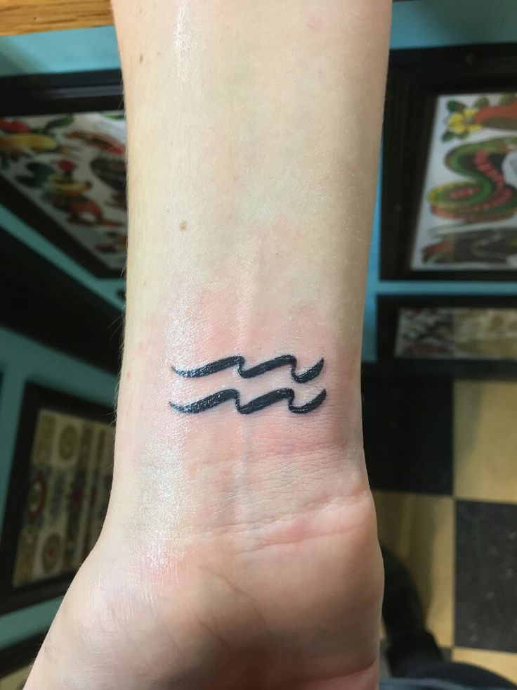 a small tattoo on the wrist of a person's left arm, which has an egyptian symbol