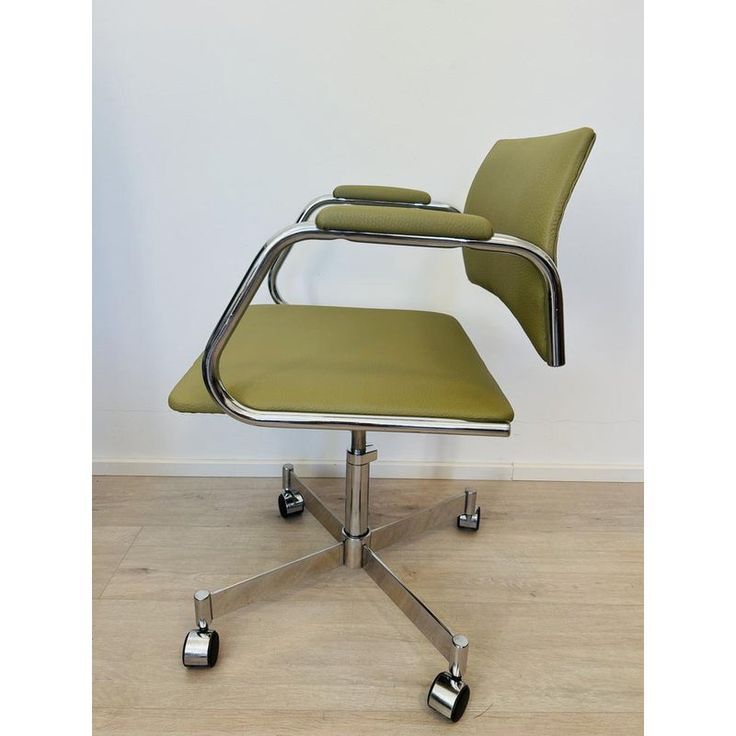 a green office chair sitting on top of a wooden floor next to a white wall