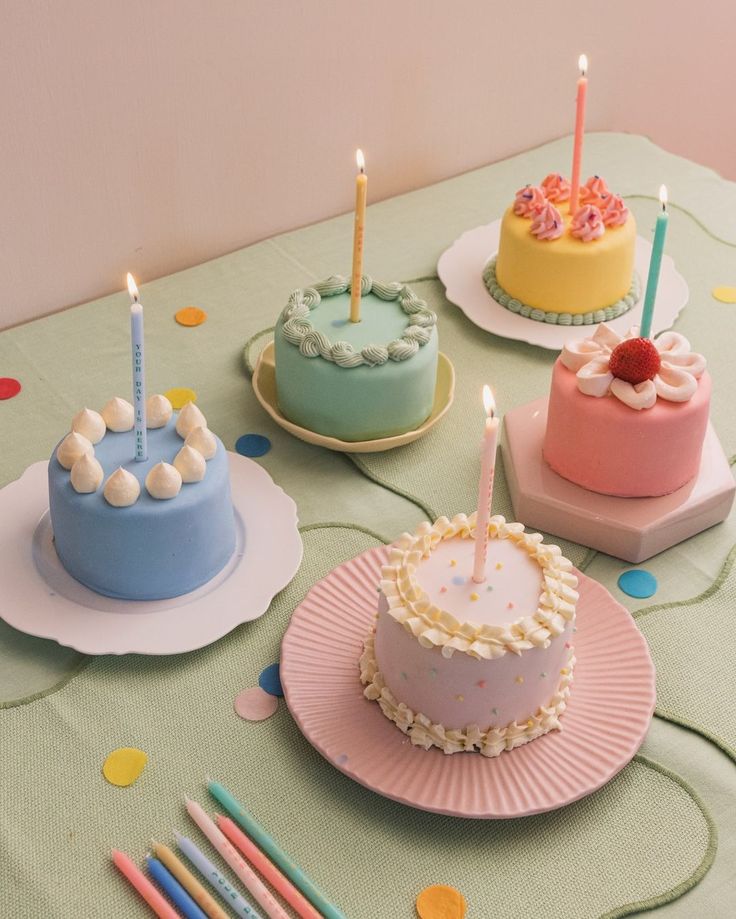 a table topped with cakes covered in frosting and lit candles on top of them