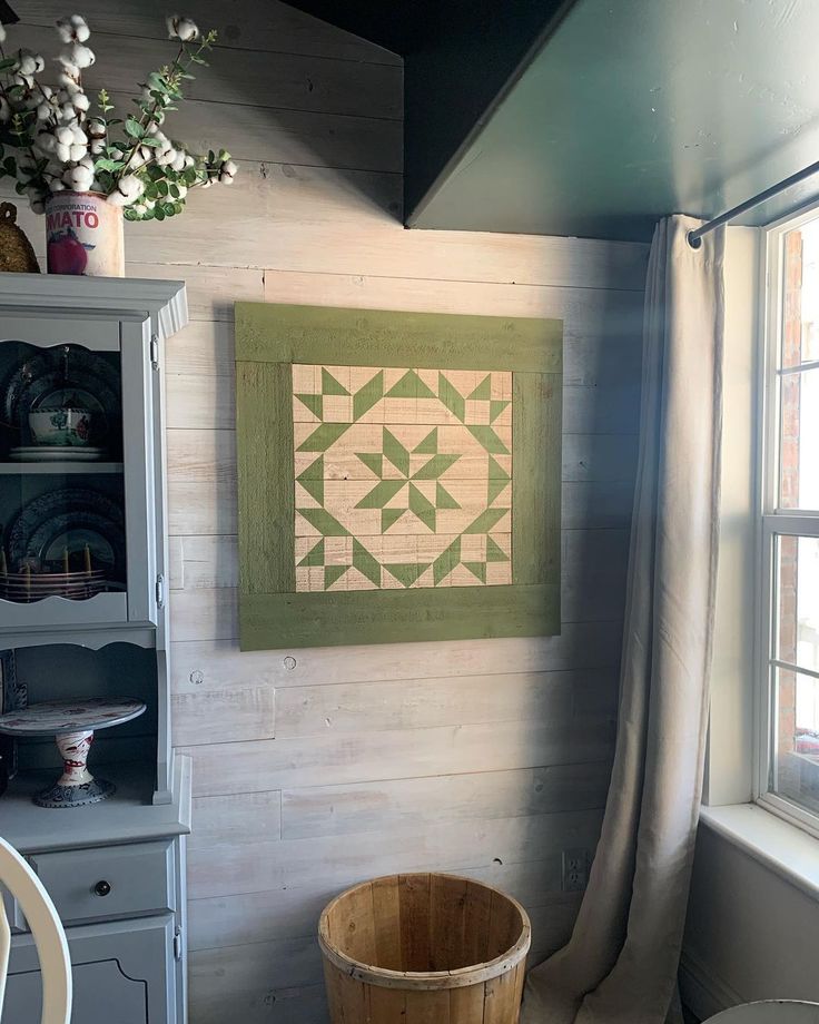 a wooden bucket sitting in front of a window next to a painting on the wall