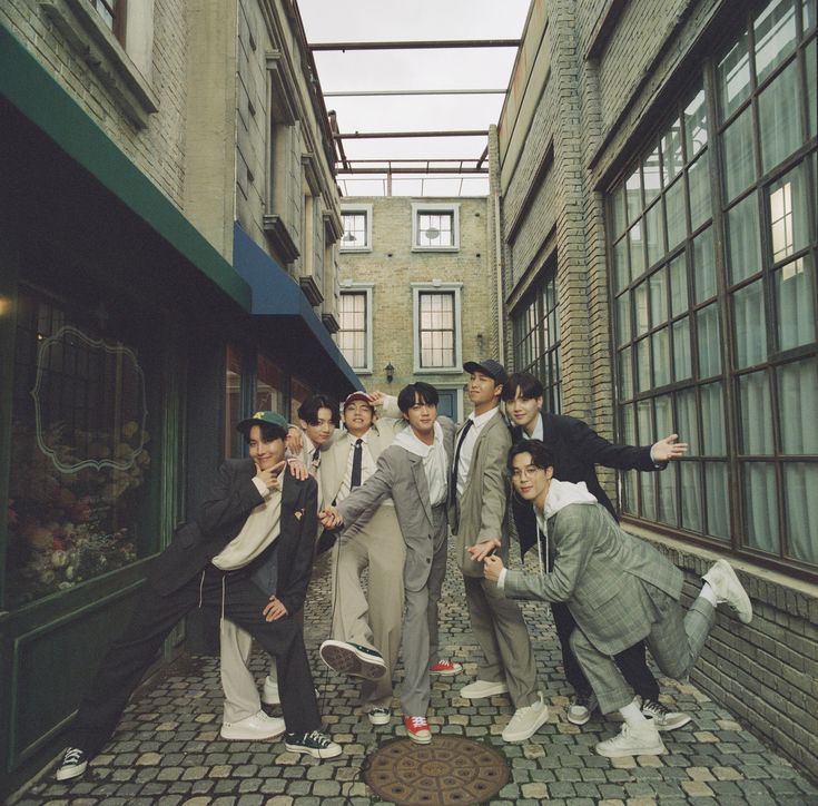 a group of young men standing next to each other in an alleyway with windows