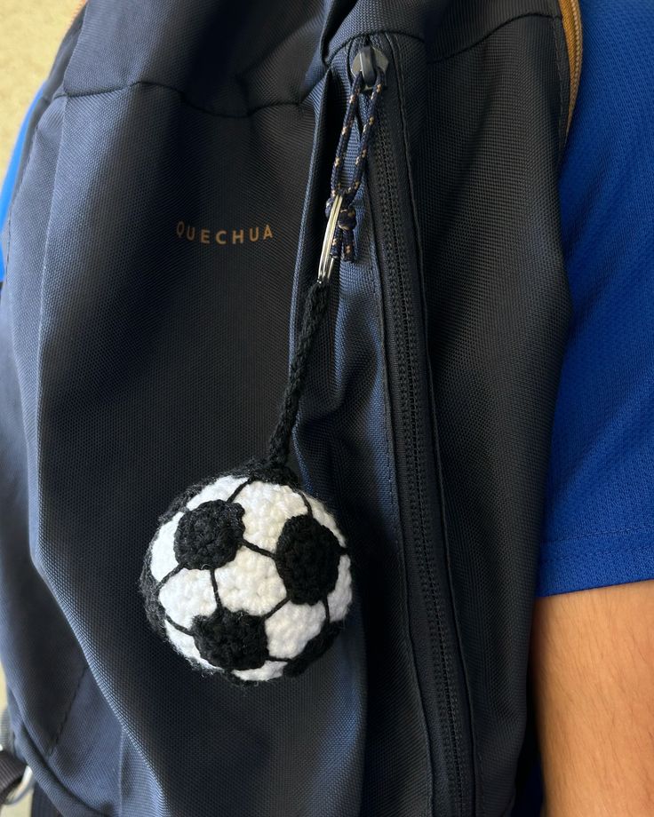 a backpack with a crocheted soccer ball hanging from it's front pocket