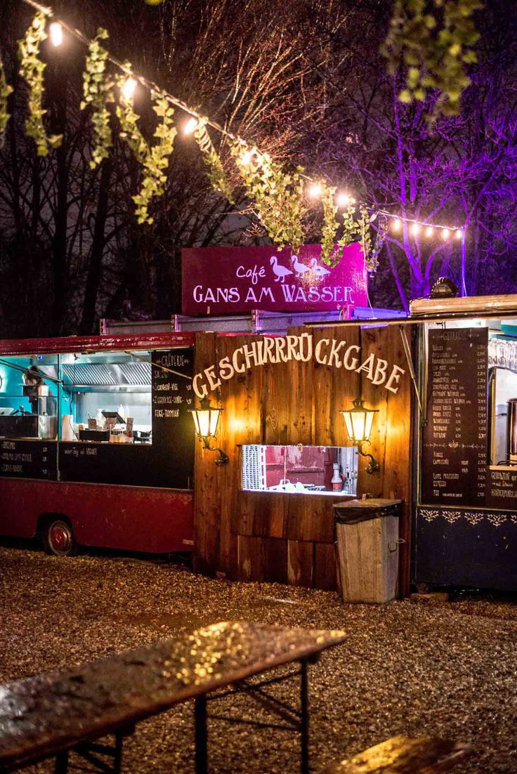 a food truck parked in front of a building with lights hanging from it's roof