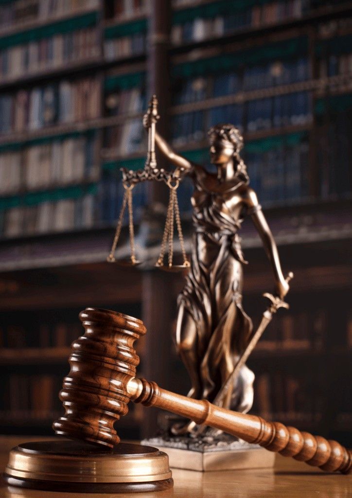 a statue of lady justice and a wooden gavel on a table in front of bookshelves