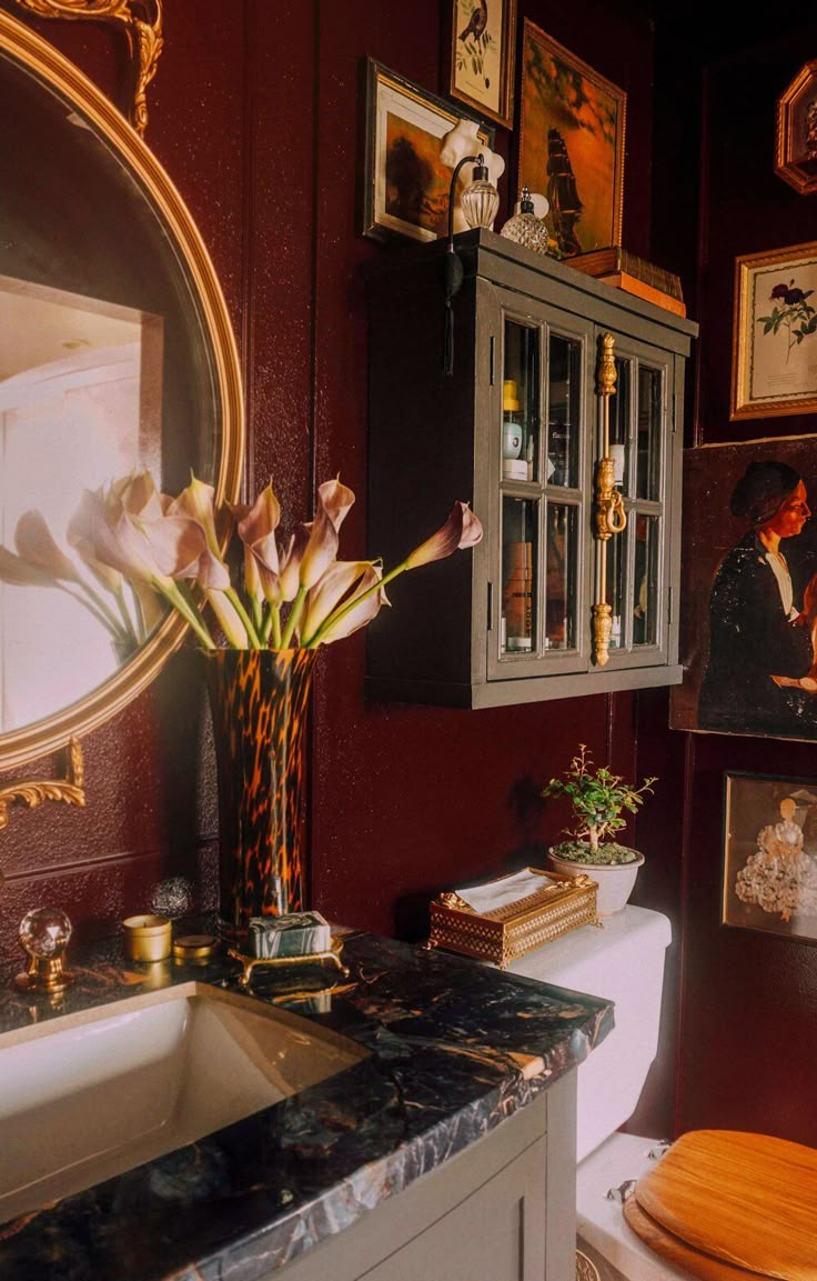 a bathroom with a sink, mirror and pictures on the wall next to it's toilet